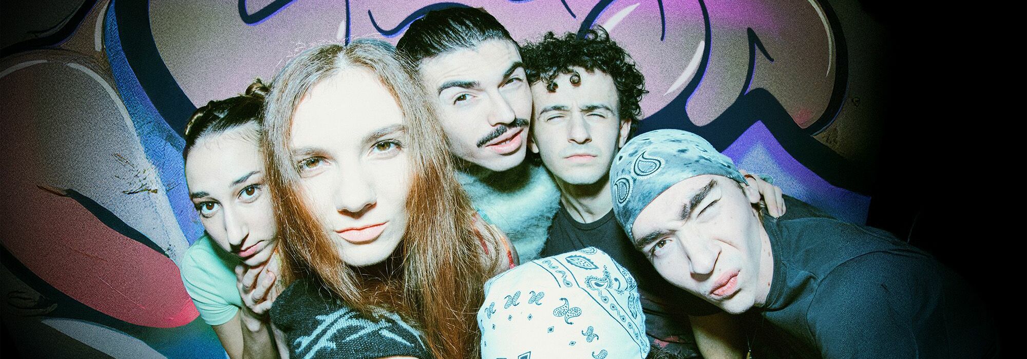 Afbeelding van de voorstelling: Groen sfeer verlichting kleurt de ruimte, een aantal personen houden briefjes geld vast, in het midden zit een man met een snor en een bontkraag, hij heeft een vrolijke blik en om hem heen zitten een aantal vrouwen.